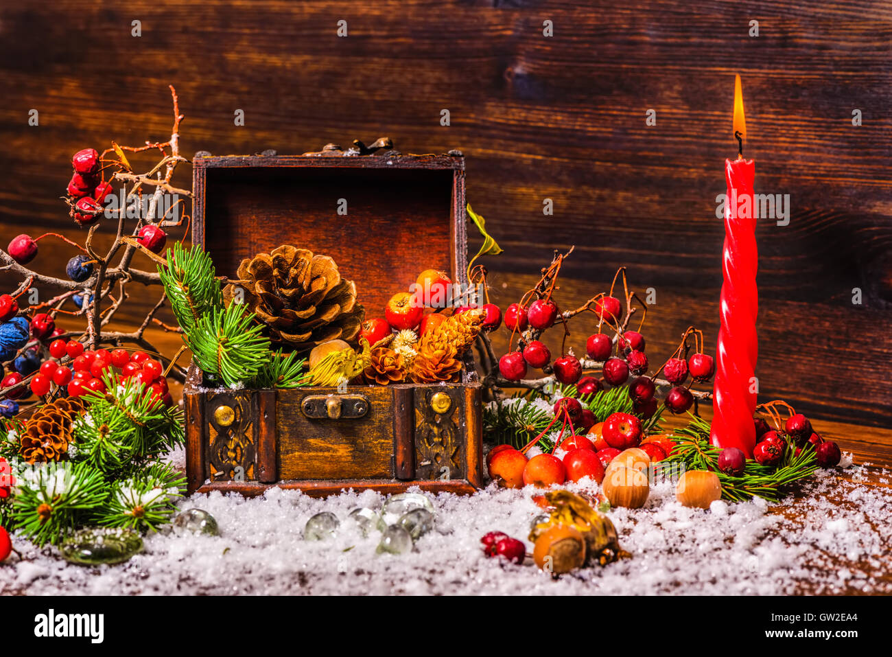 Thanksgiving-Feiertag-Hintergrund mit geöffneten Brust Schatz, Apfel, Nüssen, Zapfen, Beeren, Tanne, Kerze und Schnee, Nahaufnahme Stockfoto