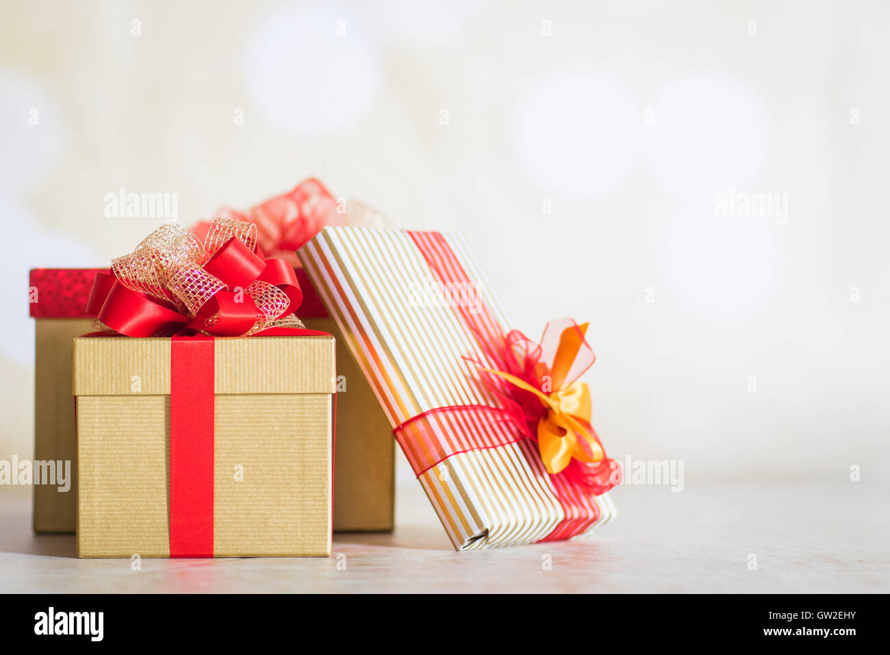 Weihnachtsgeschenke in Goldpapier mit roten Bändern gewickelt Stockfoto