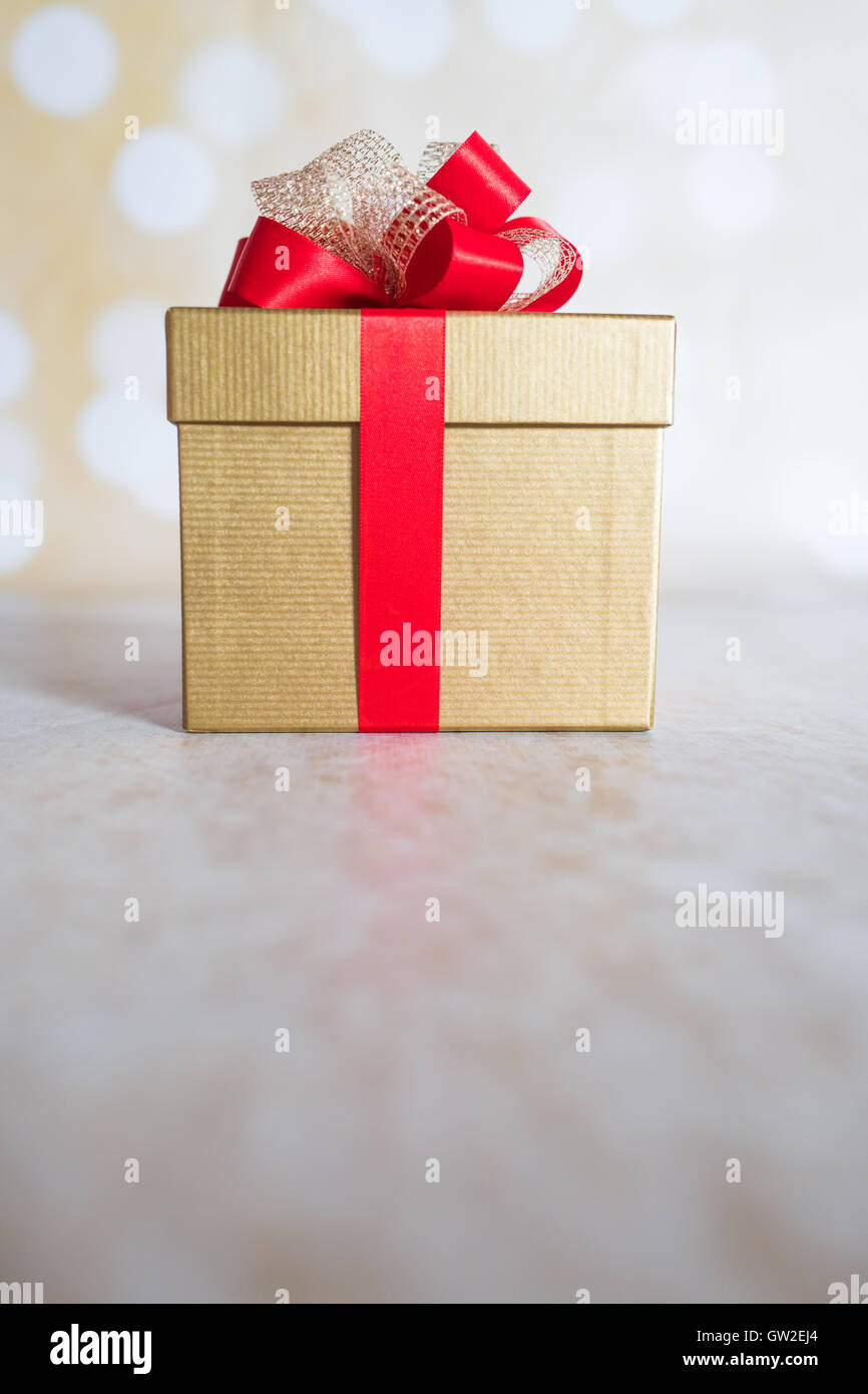 Ein Geschenk mit einer roten Schleife und Lichter im Hintergrund. Stockfoto
