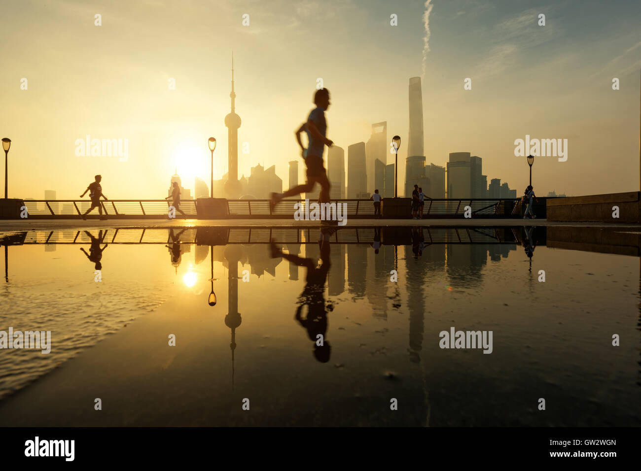 Menschen, die morgens am Huangpu-Fluss am Flussufer mit Shanghai downtown im Hintergrund laufen, in Shanghai, China. Stockfoto