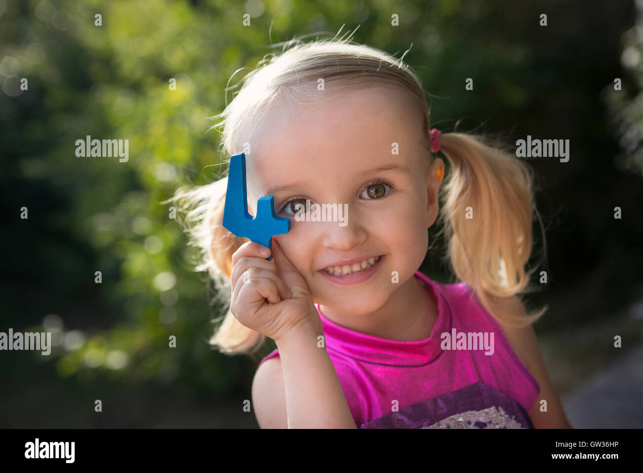 Lächelnde Mädchen Holding blaue Nummer vier Stockfoto