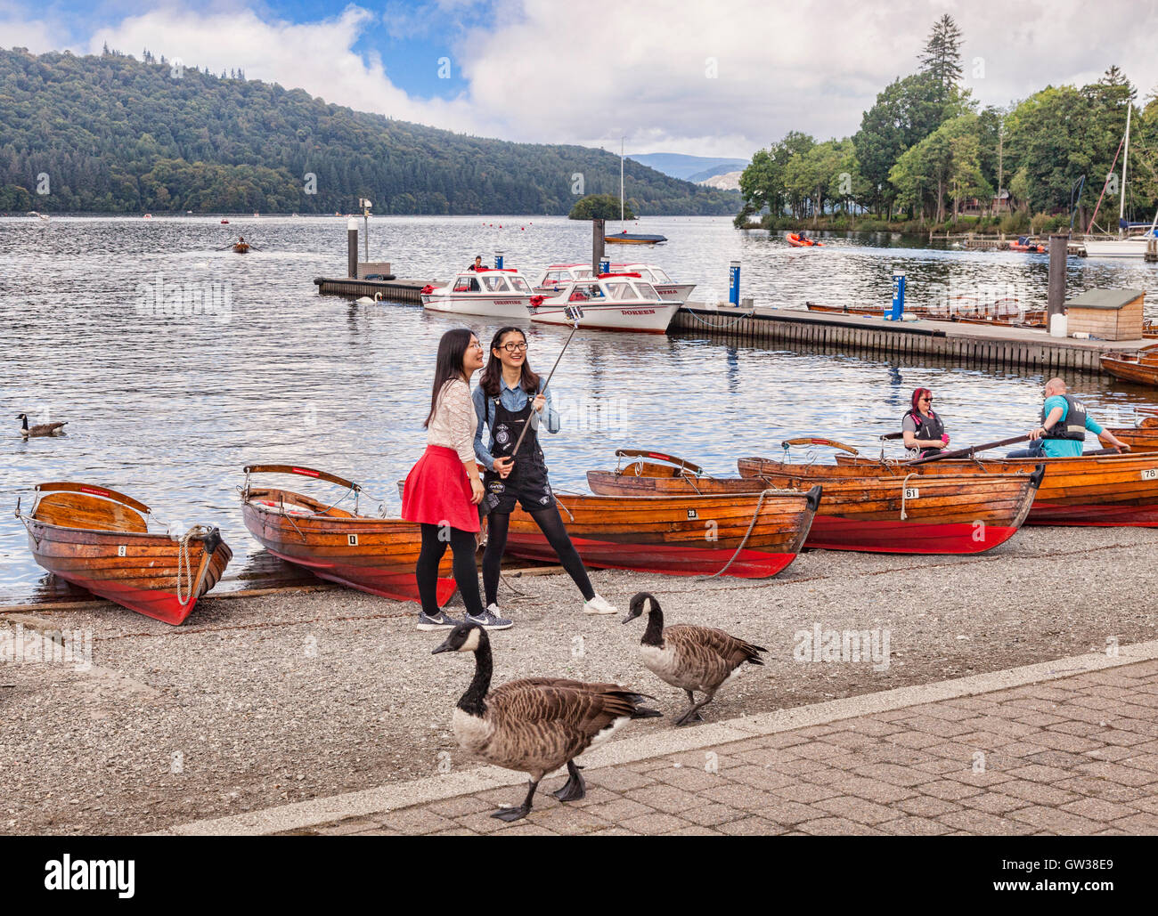 Zwei asiatische Mädchen fotografieren mit einem Selfie kleben an den Ufern des Lake Windermere, Cumbria, England, UK Stockfoto