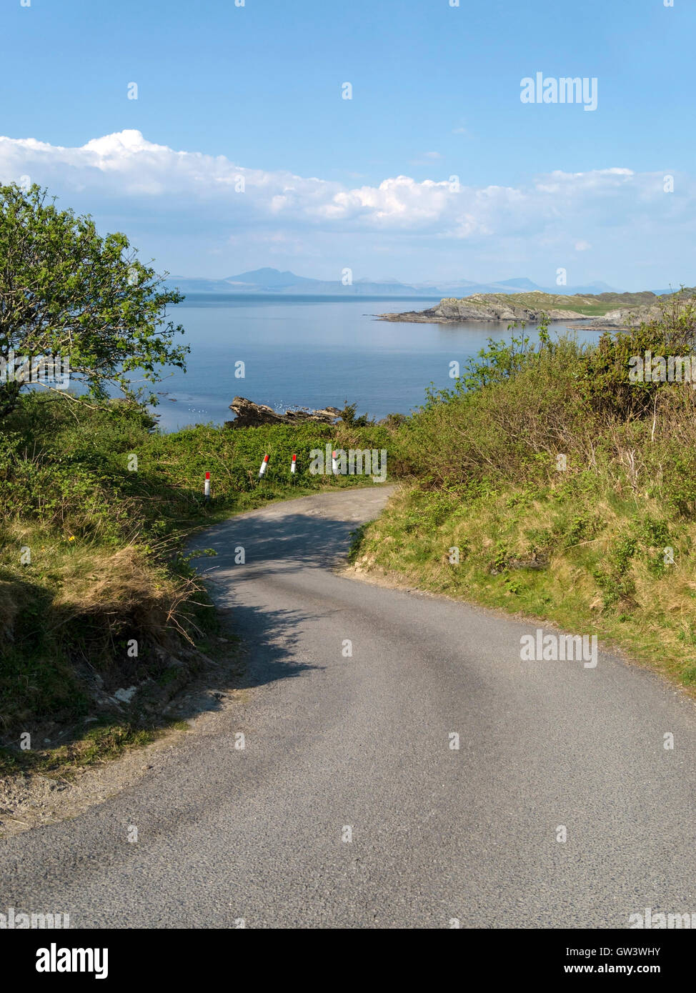 Wicklung einspurigen Straße auf der Insel Colonsay mit Blick über das Meer nach Isle of Mull in der Inneren Hebriden, Schottland, Großbritannien. Stockfoto