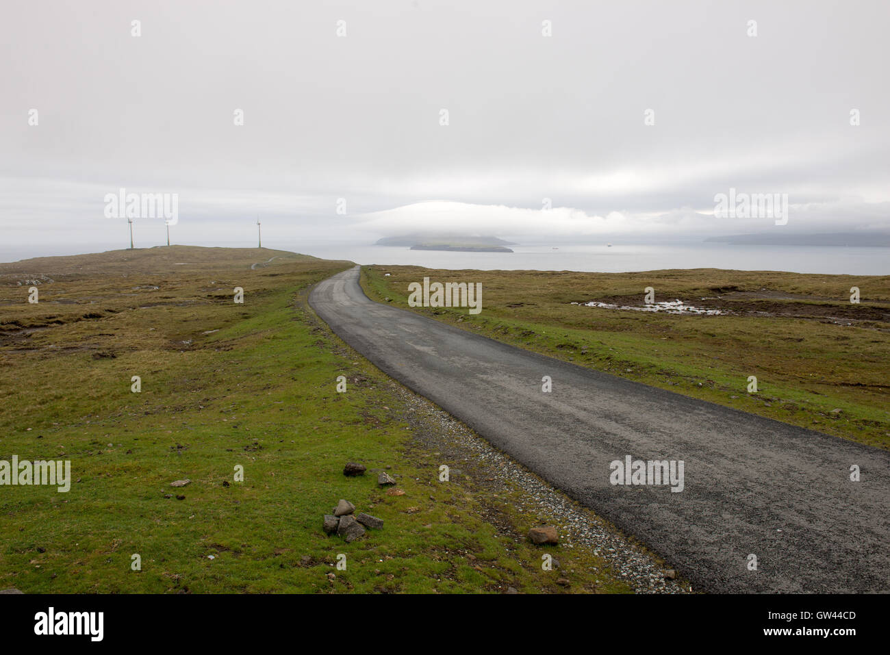 Straße auf den Färöer Inseln im Süden von Eysturoy mit Windmühlen und nolsoy Stockfoto