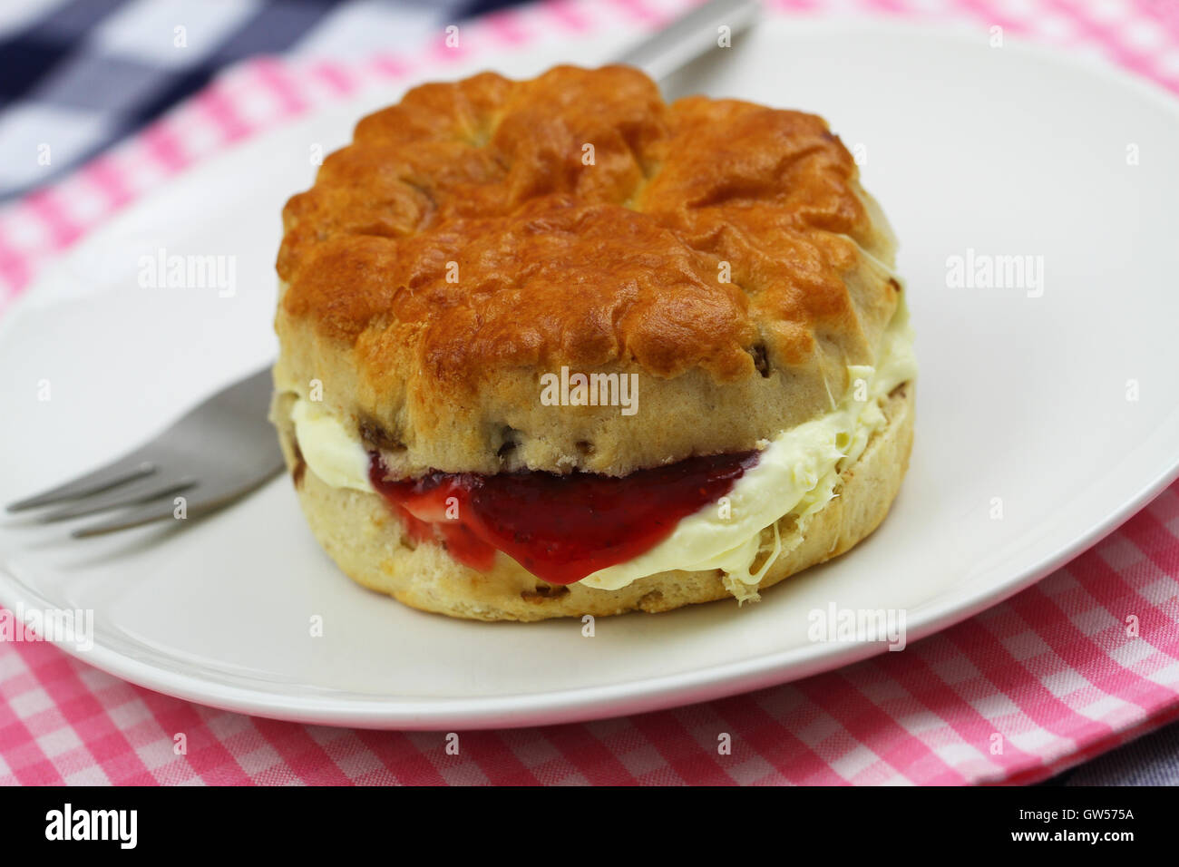 Hausgemachte englischen Scone mit traditionellen Clotted Cream und Erdbeermarmelade auf weißen Teller, Nahaufnahme Stockfoto
