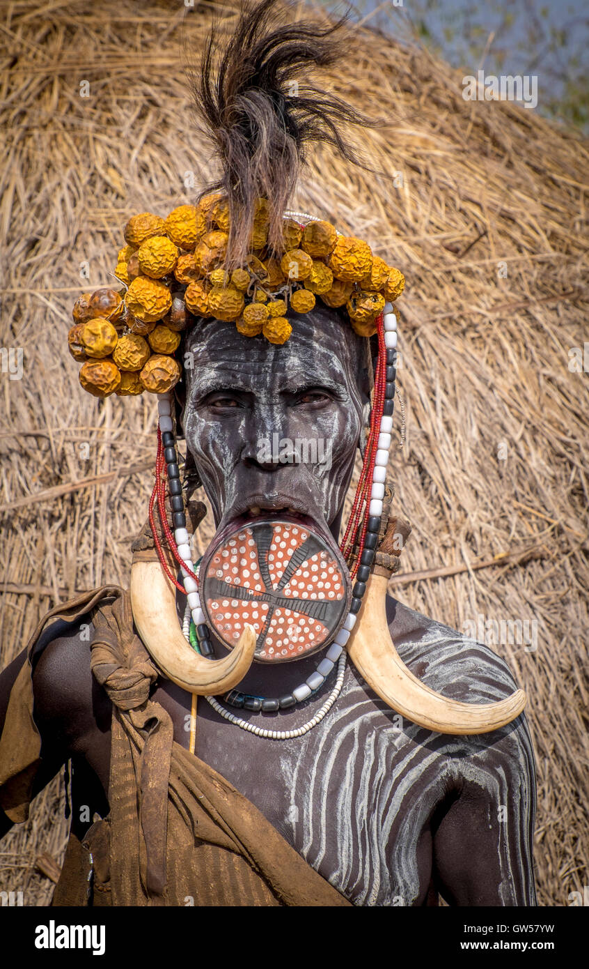 Mursi-Frau das Omo-Tal in Äthiopien mit Mundlochplatte, Body-Painting, Kopfschmuck, Federn und Knochen Ohrringe Stockfoto