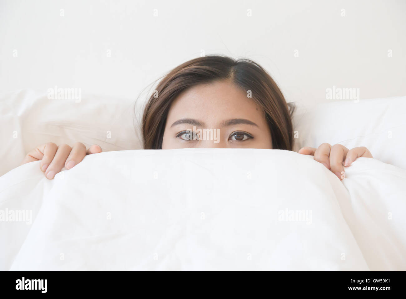 asiatische Frau liegen im Bett unter der Decke Stockfoto