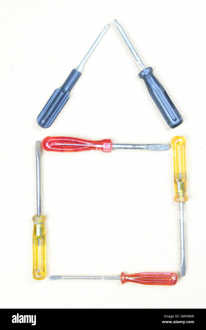 Bild von Werkzeugen in Form des Hauses. Hintergrund mit einer braunen Holzplatte. Über hell. Stockfoto