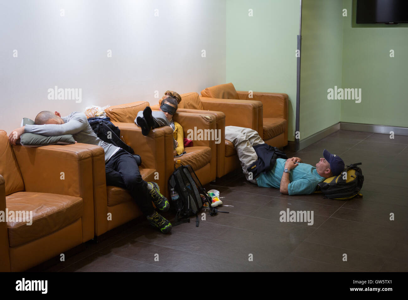 Drei Passagiere in einer Flughafen-Abflug-Lounge zu schlafen, während der Wartezeit für einen verspäteten Flug Stockfoto