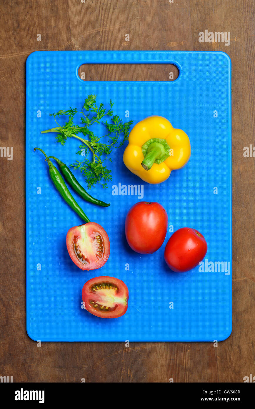 Gelbe Paprika, Tomaten, Chili und Koriander auf Schneidebrett Stockfoto