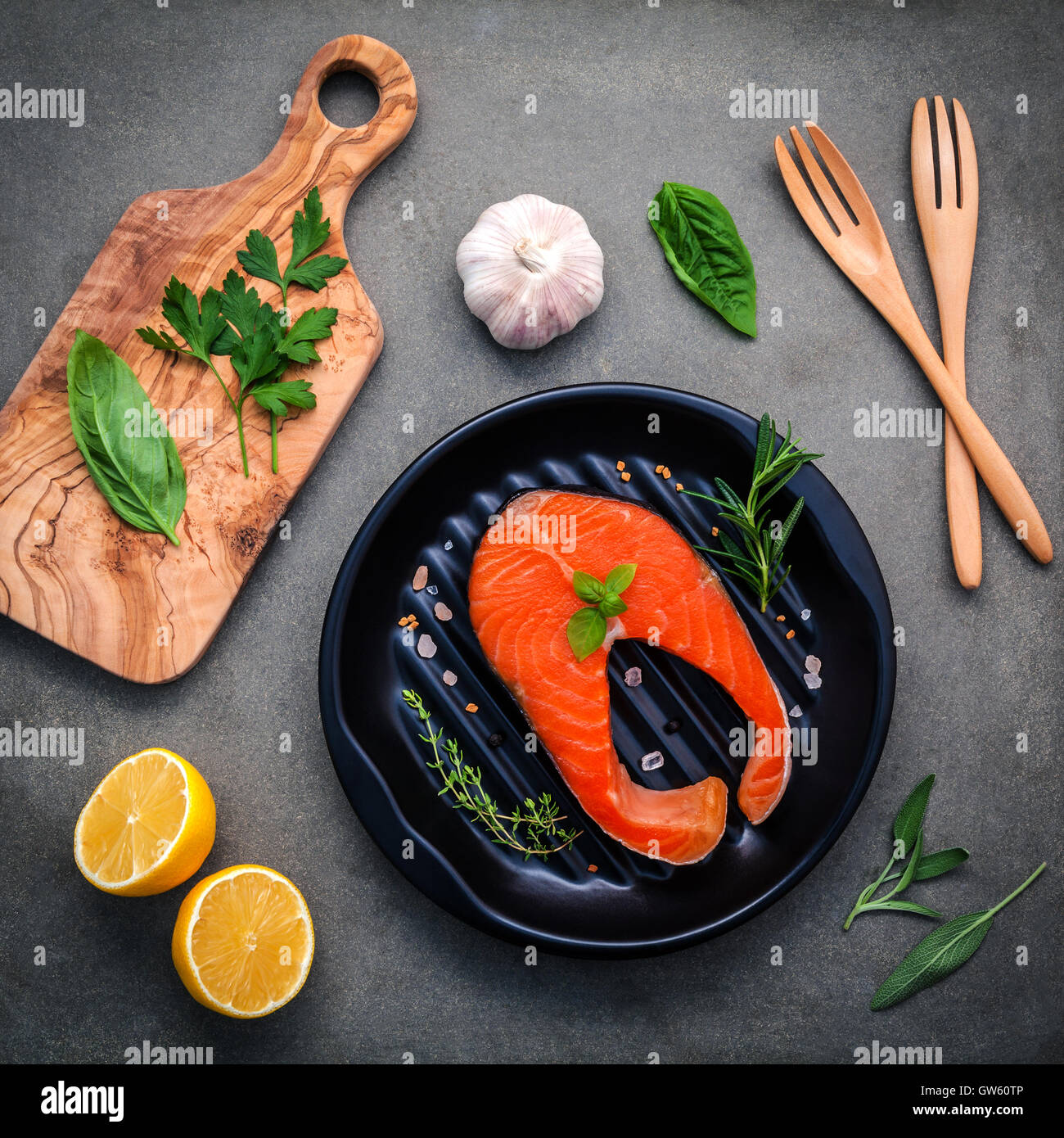Rohem Lachsfilet in der schwarzen Platte mit Zutaten Olivenöl, Himalaya-Salz und Kräuter Basilikum, Fenchel, Salbei, Rosmarin, Stockfoto
