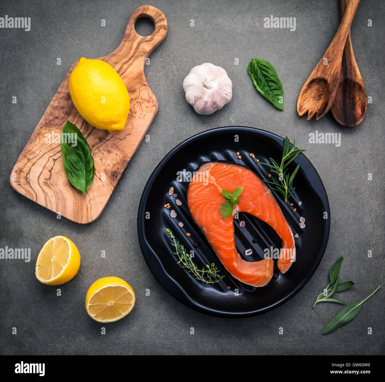 Rohem Lachsfilet in der schwarzen Platte mit Zutaten Olivenöl, Himalaya-Salz und Kräuter Basilikum, Fenchel, Salbei, Rosmarin, Stockfoto