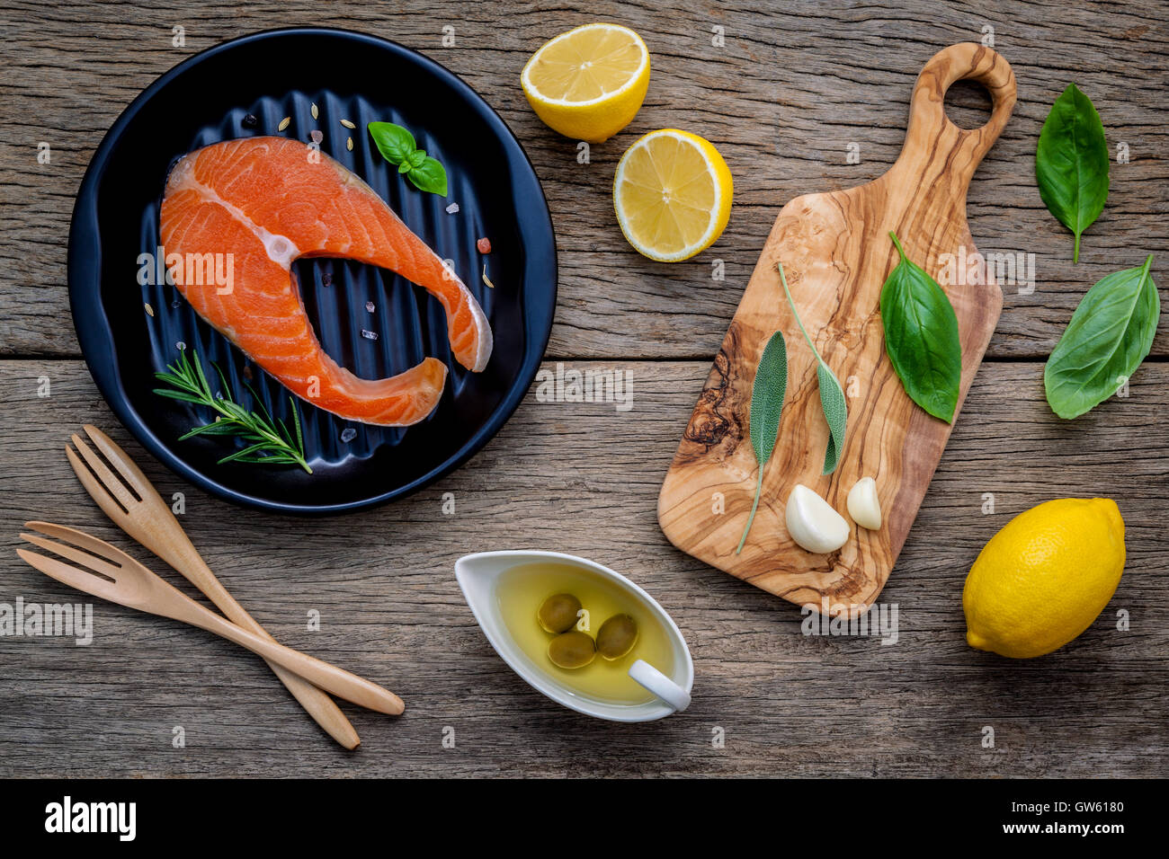 Rohem Lachsfilet in der schwarzen Platte mit Zutaten Olivenöl, Himalaya-Salz und Kräuter Basilikum, Fenchel, Salbei, Rosmarin, Stockfoto