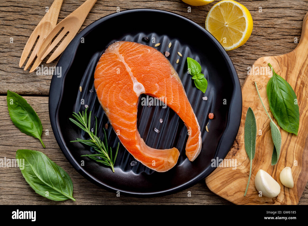 Rohem Lachsfilet in der schwarzen Platte mit Zutaten Olivenöl, Himalaya-Salz und Kräuter Basilikum, Fenchel, Salbei, Rosmarin, Stockfoto