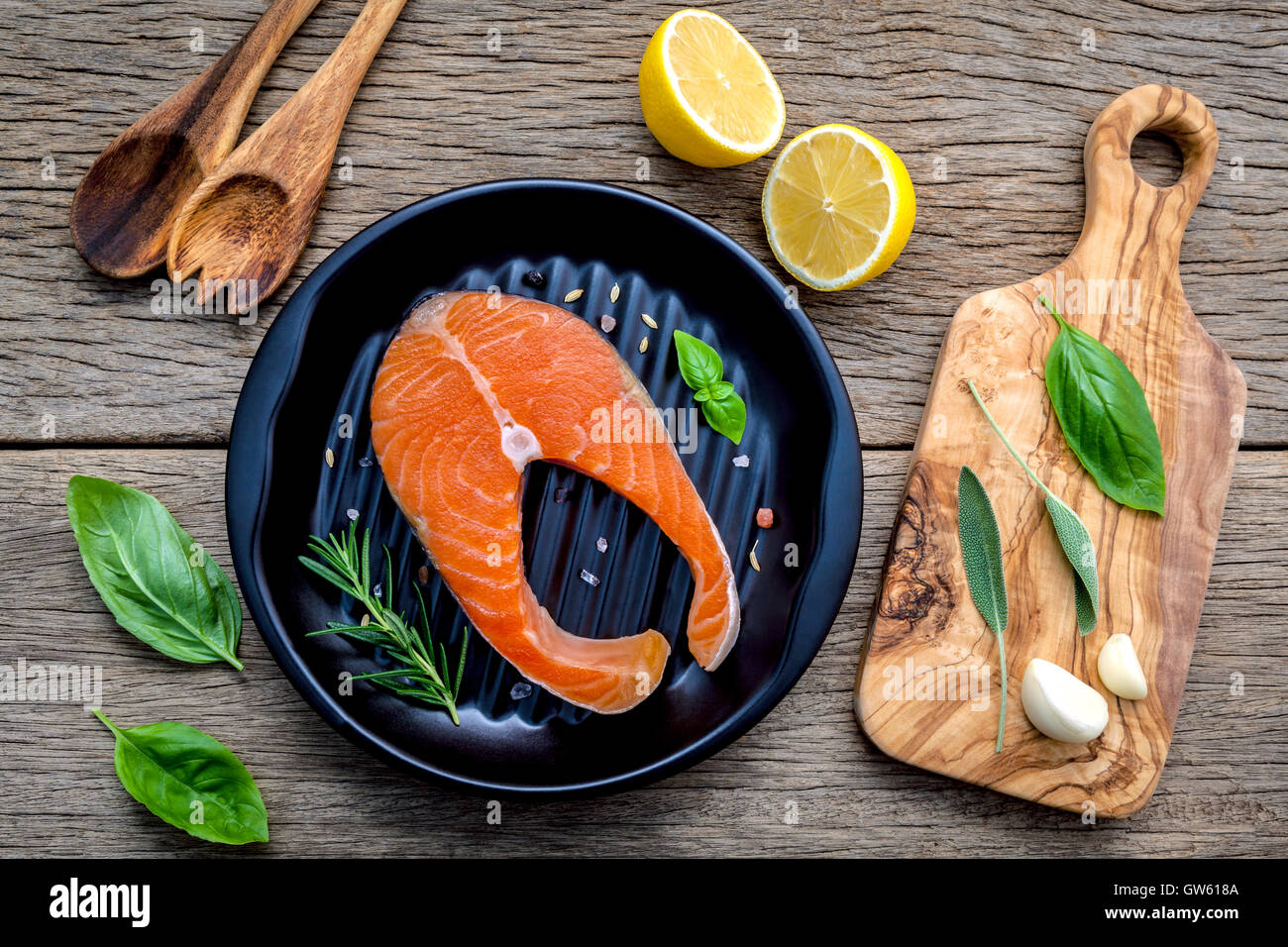 Rohem Lachsfilet in der schwarzen Platte mit Zutaten Olivenöl, Himalaya-Salz und Kräuter Basilikum, Fenchel, Salbei, Rosmarin, Stockfoto