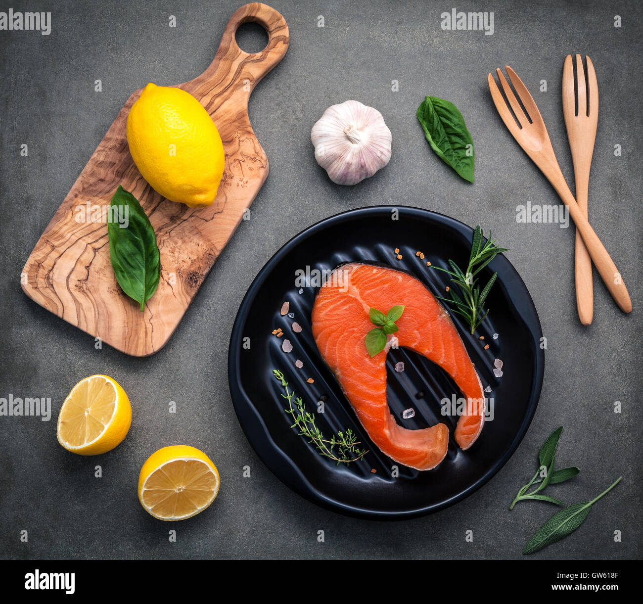 Rohem Lachsfilet in der schwarzen Platte mit Zutaten Olivenöl, Himalaya-Salz und Kräuter Basilikum, Fenchel, Salbei, Rosmarin, Stockfoto