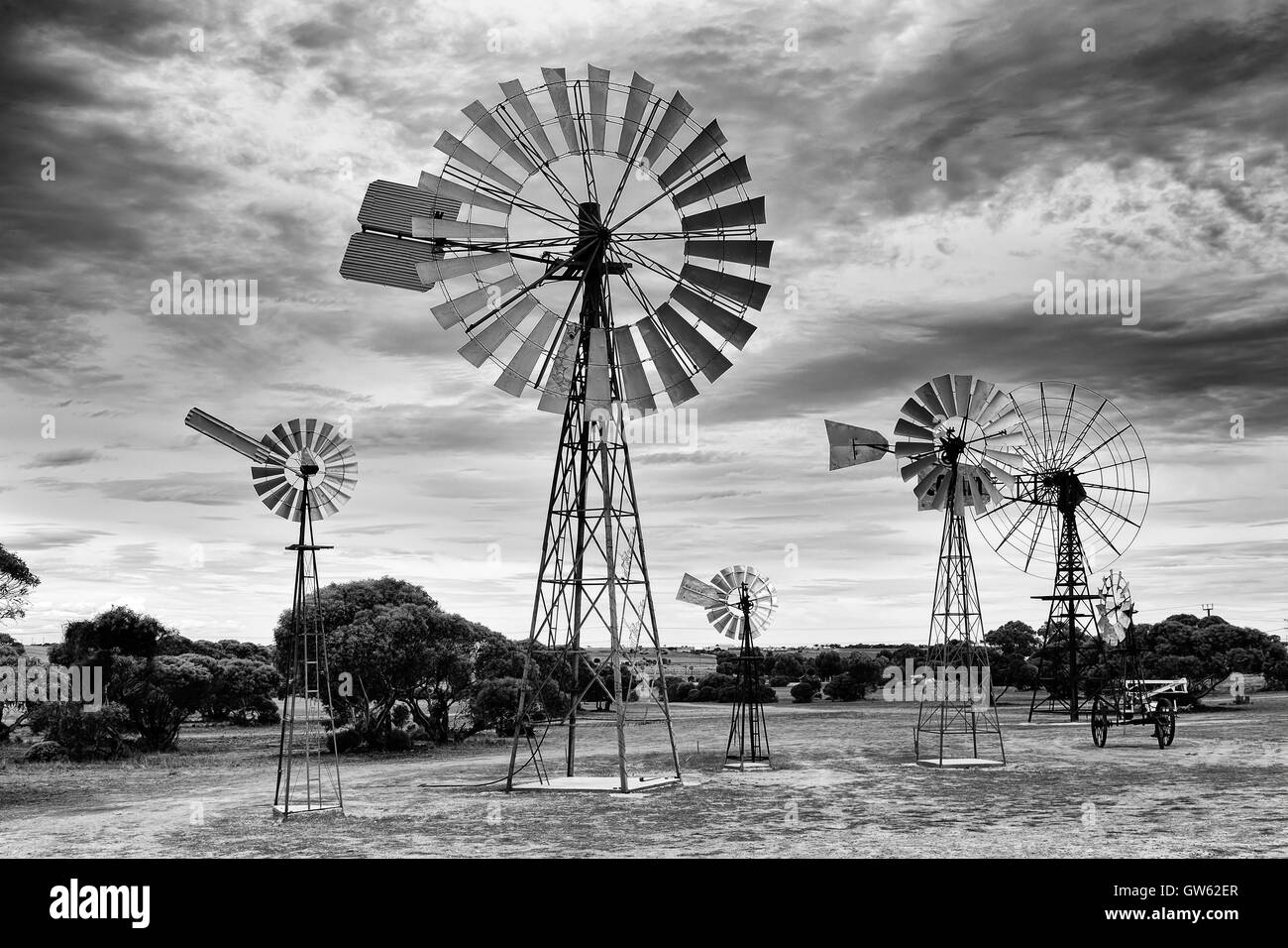 Array von historischen traditionellen Windmühlen in ländlichen Südaustralien gegen bewölktem Himmel an einem heißen Sommertag in schwarz-weiß. Stockfoto