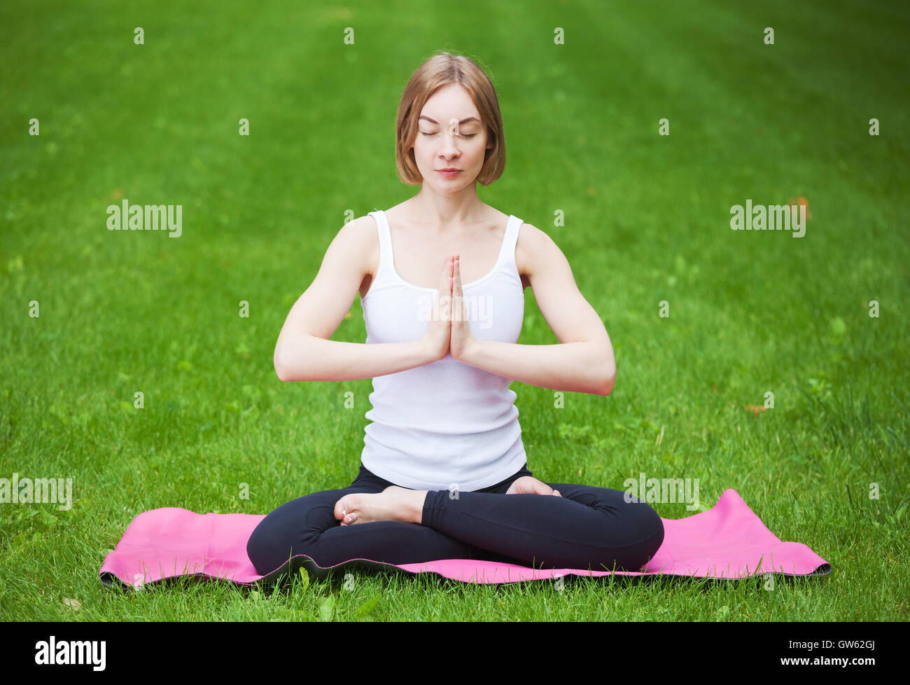 Junge schöne Frau, die beim Yoga im Park. Stockfoto