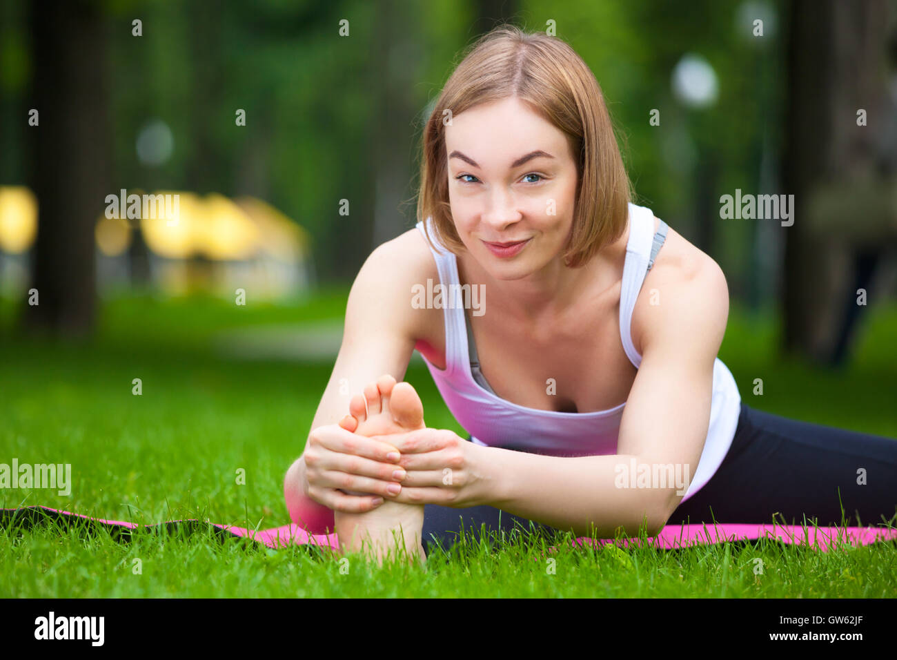 Junge schöne Frau streckt sich im Park. Stockfoto