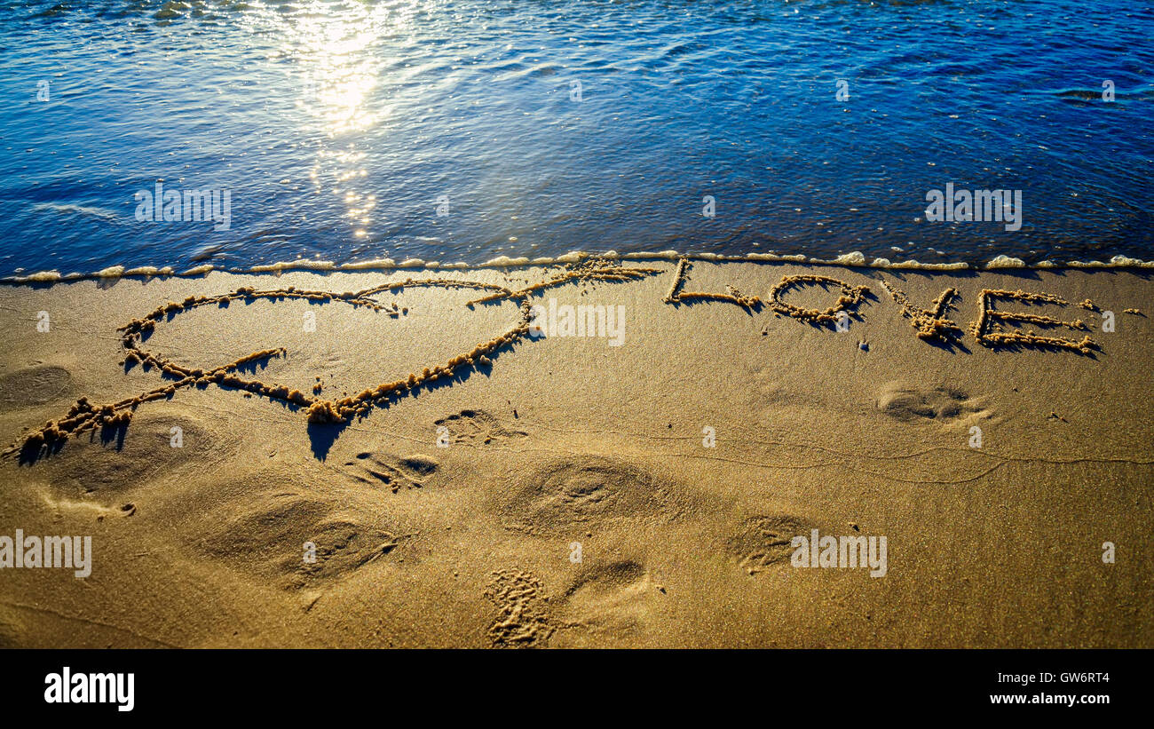 Herz und Pfeil gezeichnet auf dem Sand am Strand.  Liebe-Konzept Stockfoto