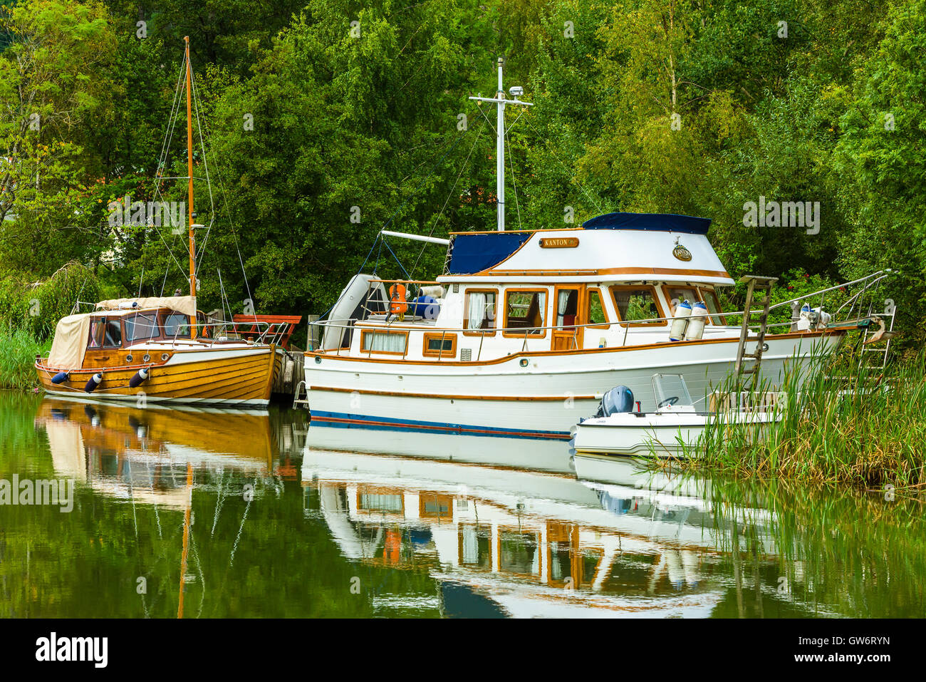 Kungalv, Schweden - 8. September 2016: Der Verkauf von neuen Booten steigen. Drei Boot der anderen Art vertäut am Flussufer mit fores Stockfoto