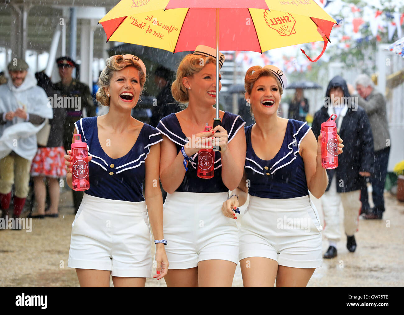Die Dolly-Mädchen (l-R Hannah Woolley, Helen Patching, Katy Osborne, aus London), ein enger Harmonie Vintage Trio, in Vintage Seemann Outfits gekleidet sind abgebildet, während die Nässe beim Goodwood Revival.   Das Goodwood Revival ist eine dreitägige Festival jedes Jahr im September im Goodwood Circuit seit 1998 für die Arten von Straßenrennen Autos und Motorrad, die in der Schaltung original Zeitraum teilgenommen haben würde – 1948 – 1966. Stockfoto