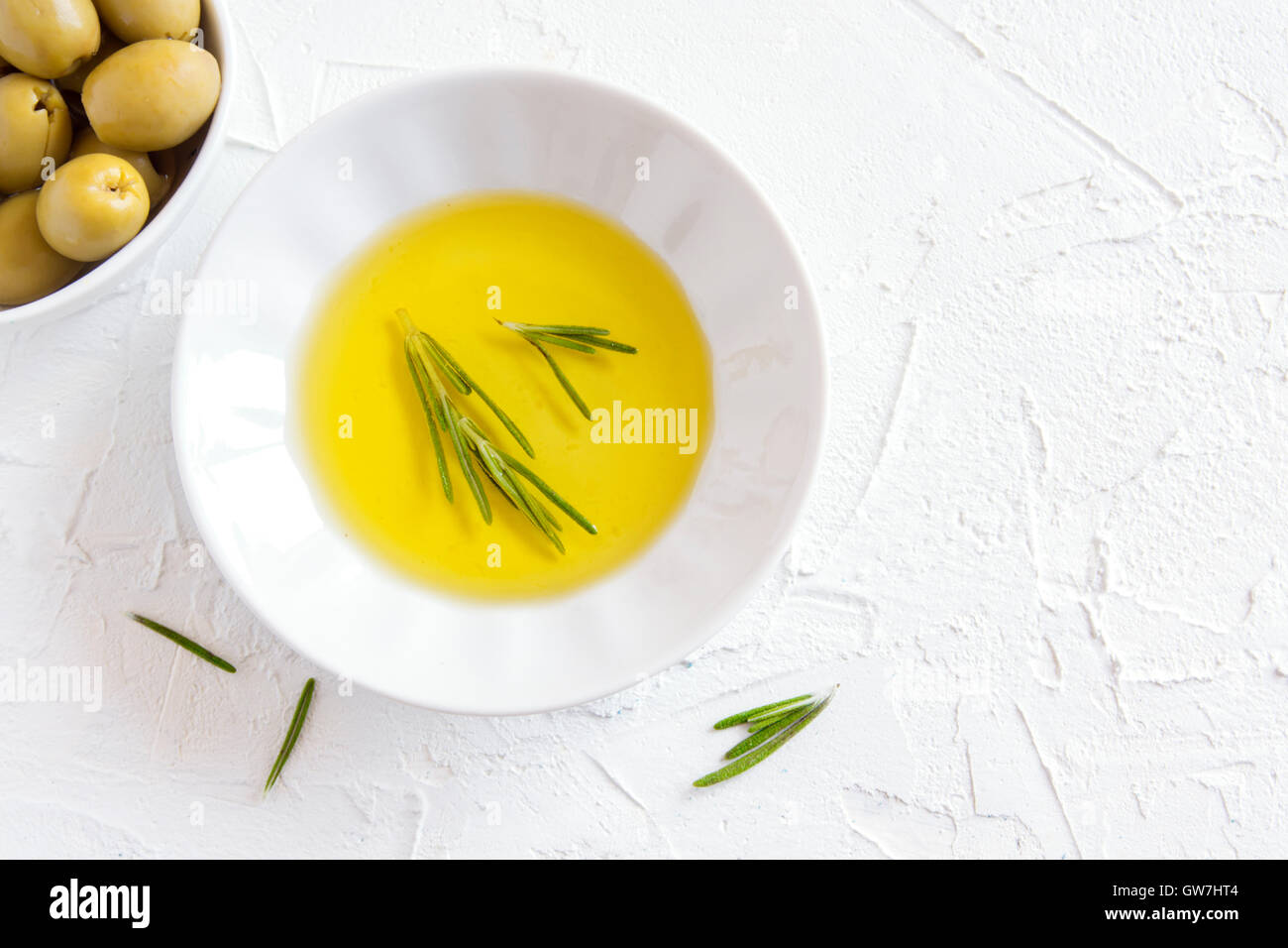 Bio-Olivenöl mit Rosmarin über weißen Stein Hintergrund mit Textfreiraum, gesunde Ernährung Konzept Stockfoto