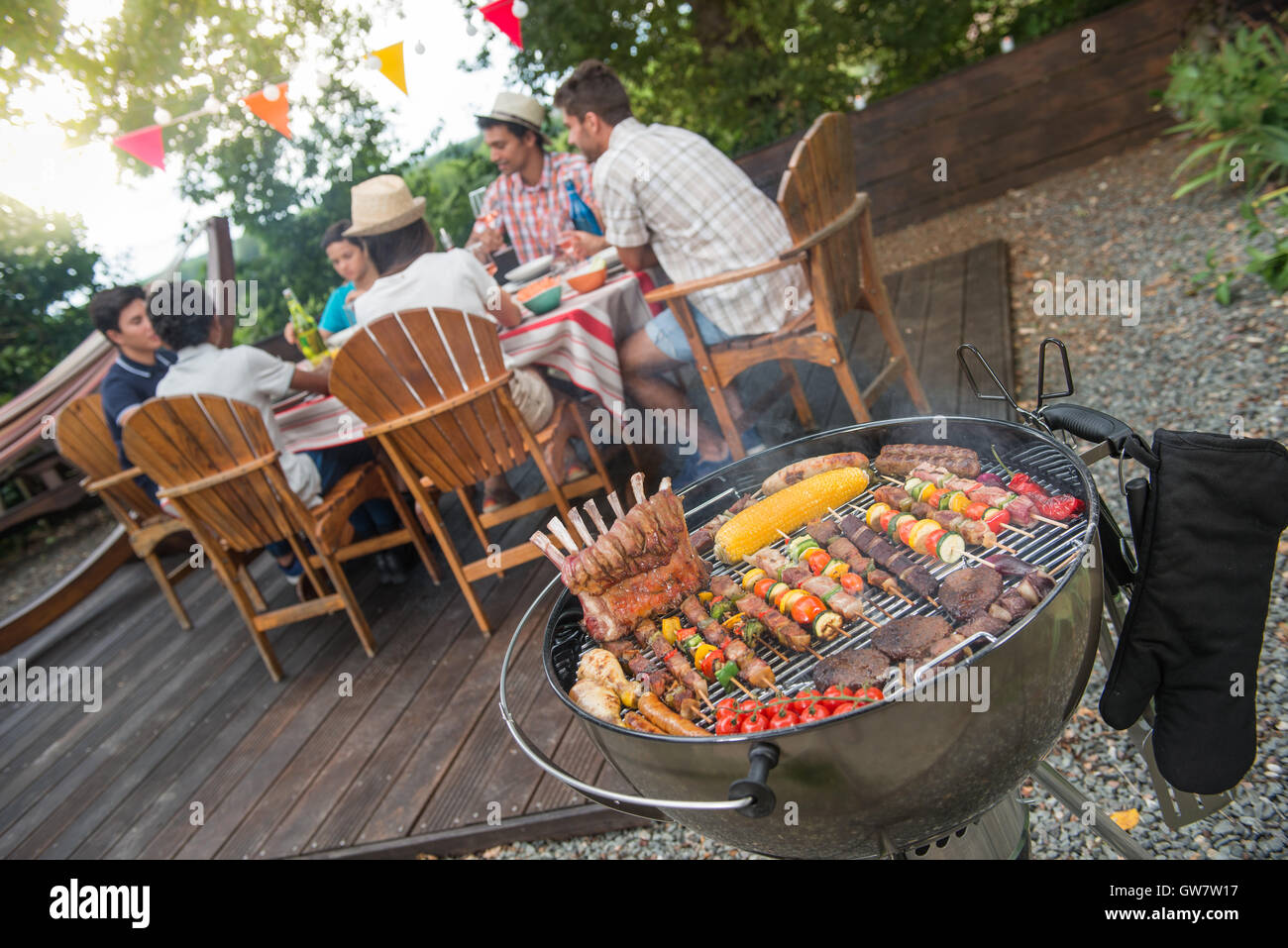 Mann, grillen Fleisch am Grill im Garten-Partei, in den Hintergrund-Freunden  Essen und trinken Stockfotografie - Alamy