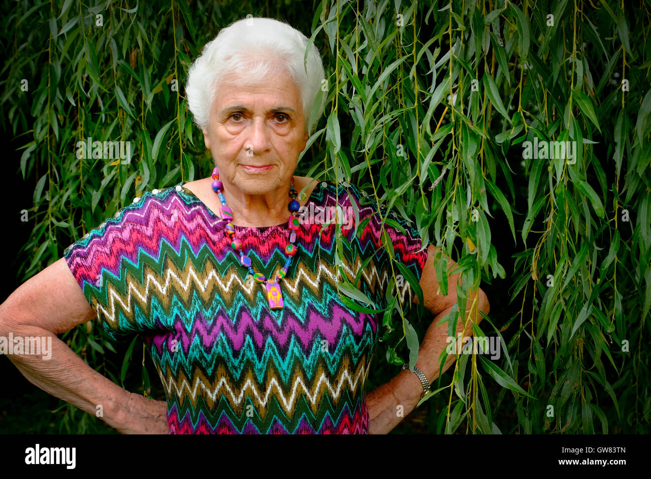 Porträt einer ausgereiften und böse Frau mit weißem Haar und eine bunte Bluse Stockfoto