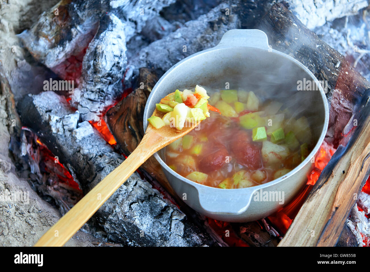 Kochen am Feuer bei Picknick, zubereitet im Kessel auf Holz, Kartoffeln und Tomaten, gesunde vegetarische Ernährung Stockfoto