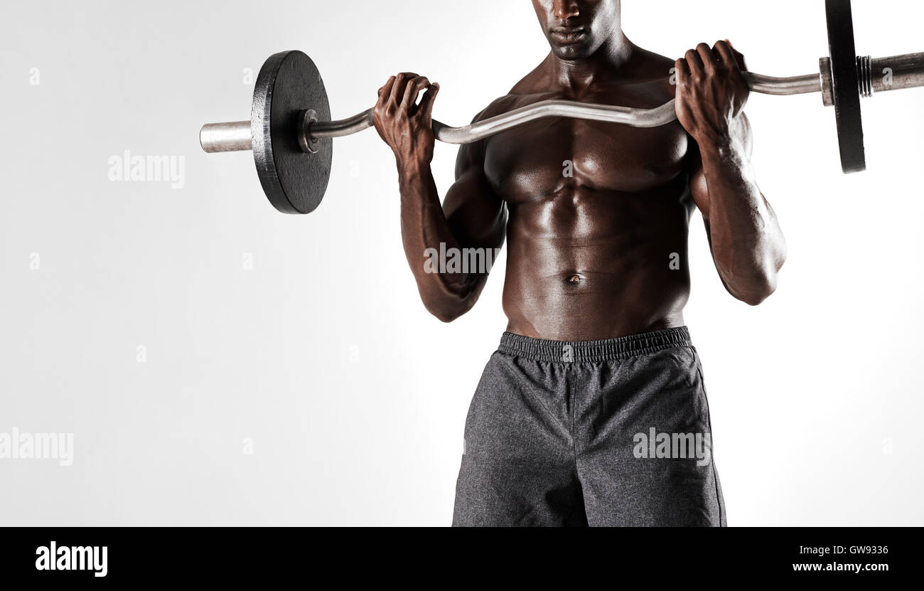 Schuss von Fit Jüngling nacktem Oberkörper heben Langhantel vor grauem Hintergrund. Jungen muskulösen Mann Training mit Gewichten. Stockfoto