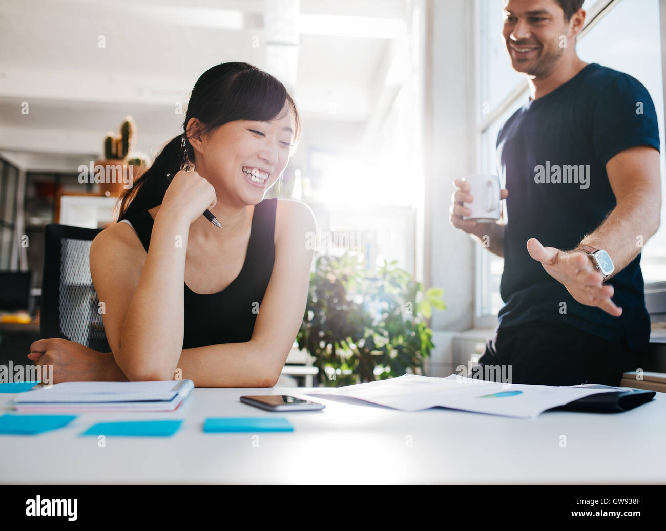 Aufnahme von zwei jungen Geschäftspartnern neue Ideen zu diskutieren und lächelnd. Junge Menschen zusammen arbeiten im Büro. Stockfoto