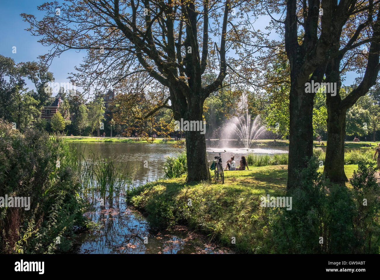 Junge Menschen entspannend in der Nähe von See und Brunnen im beliebten Vondelpark an sonnigen Tag im September, Amsterdam, Niederlande Stockfoto