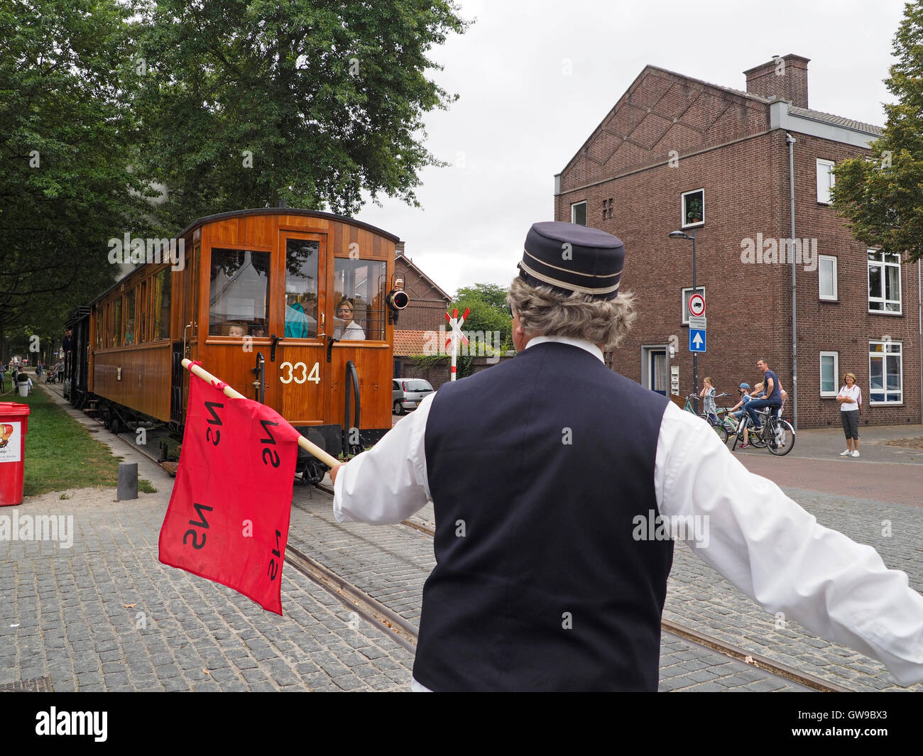 In der Vergangenheit begleitet ein Mann mit einer roten Fahne der Dampfstraßenbahn, um andere Verkehrsteilnehmer an Kreuzungen wie diese in Breda zu warnen. Stockfoto