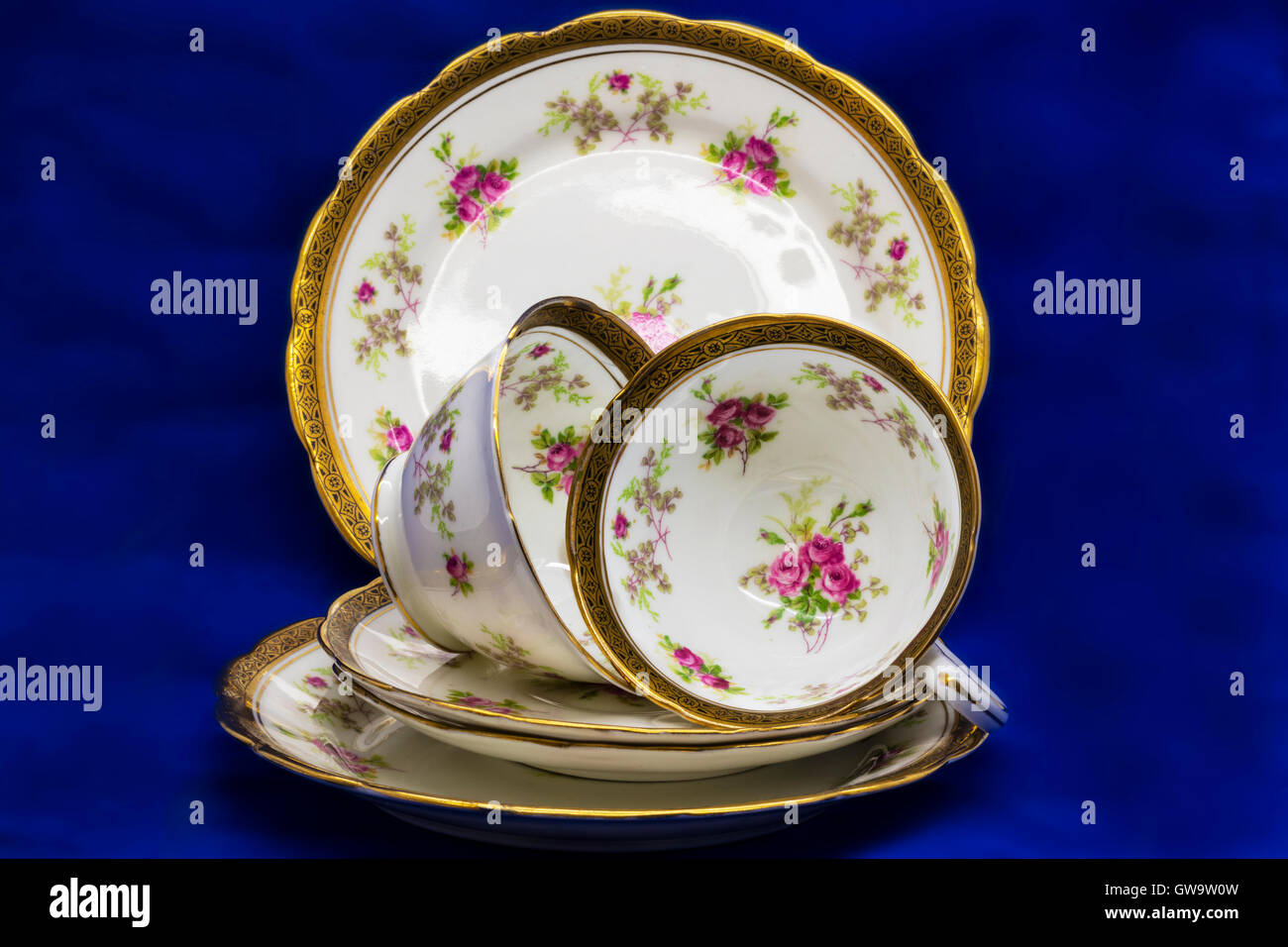 Antikes Porzellan Teetassen, Untertassen und Teller Kuchen auf blauem Hintergrund. Stockfoto
