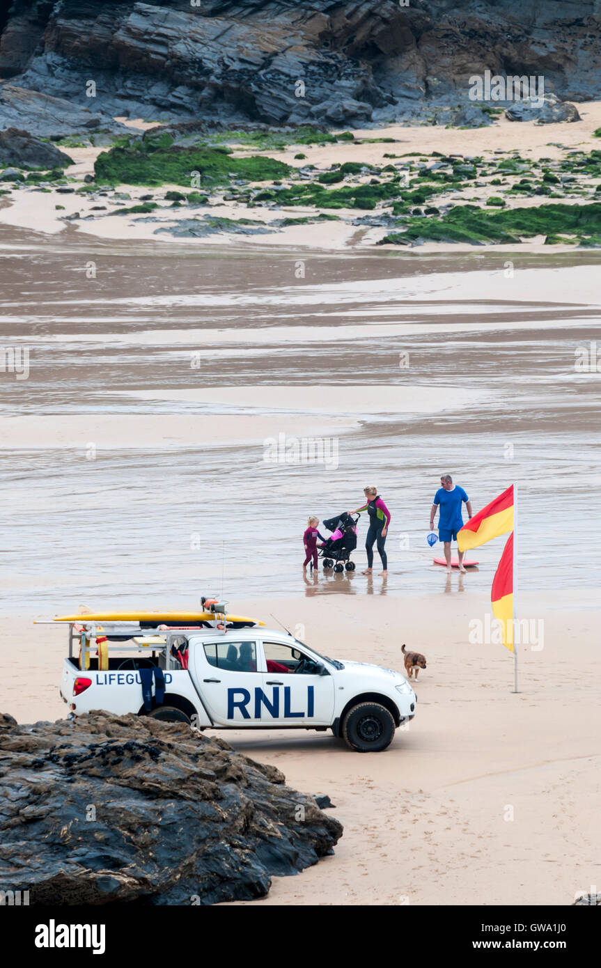 Rettungsschwimmer beobachten Schwimmer zwischen roten & gelbe Sicherheitsflaggen am Strand von Treyarnon Bay in Cornwall. Stockfoto