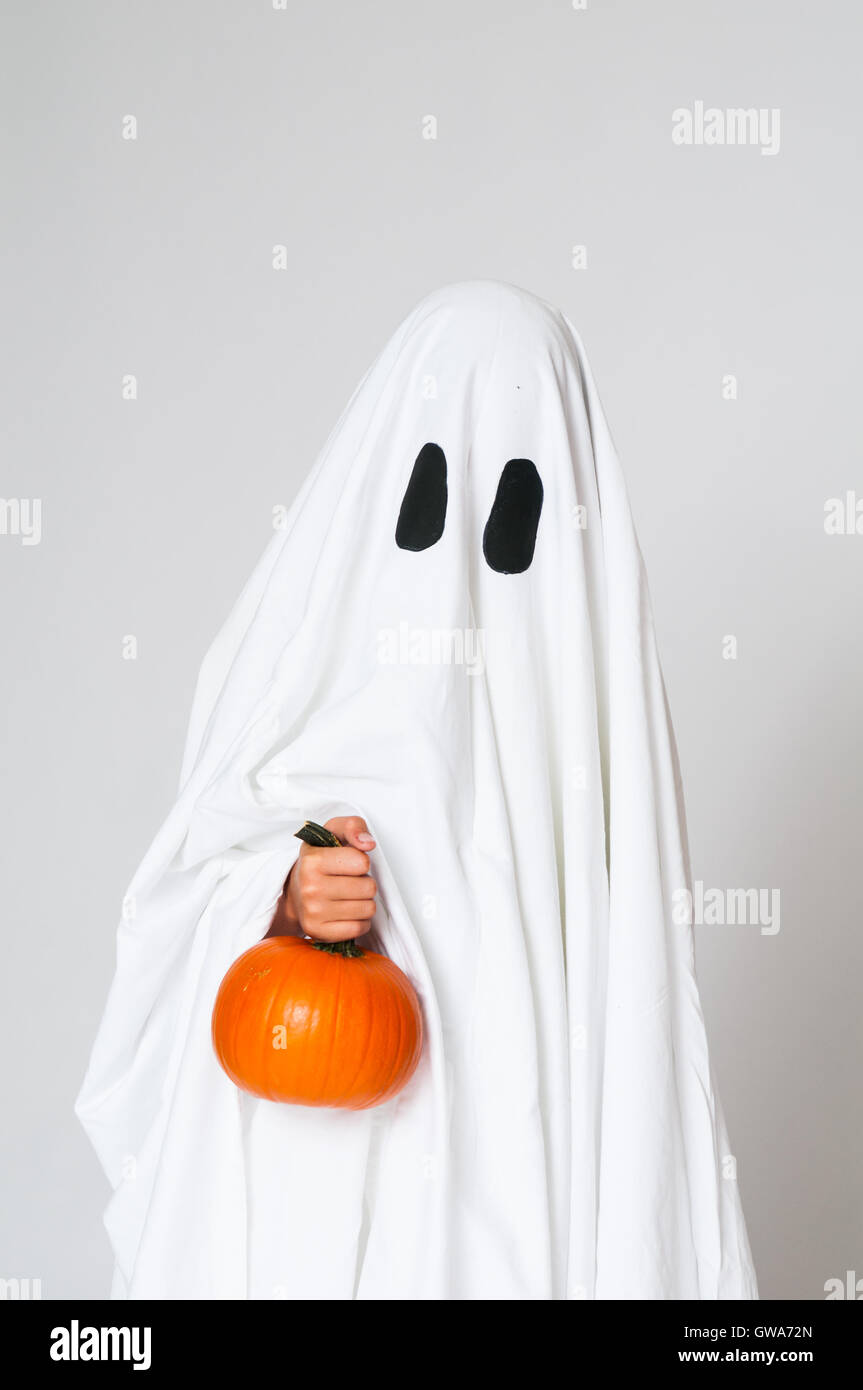 Kind als ein Gespenst hält einen Kürbis für Halloween verkleidet Stockfoto