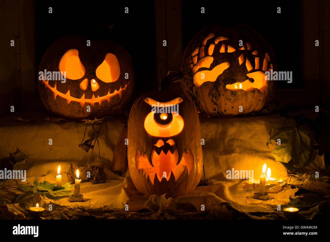 Fotomontage von drei Kürbisse zu Halloween. Jack, schrecklichen Hände und einem Zyklopen Kürbis gegen eine alte Fenster verlässt Stockfoto
