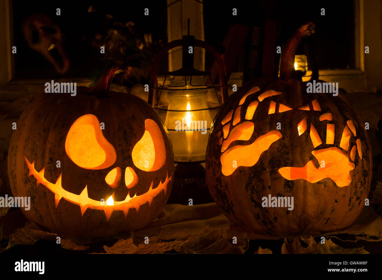 Fotomontage von zwei Kürbisse zu Halloween. Jack und schrecklich Hände gegen eine alte Fenster, trockene Blätter und ein schreckliches Gespenst in Stockfoto