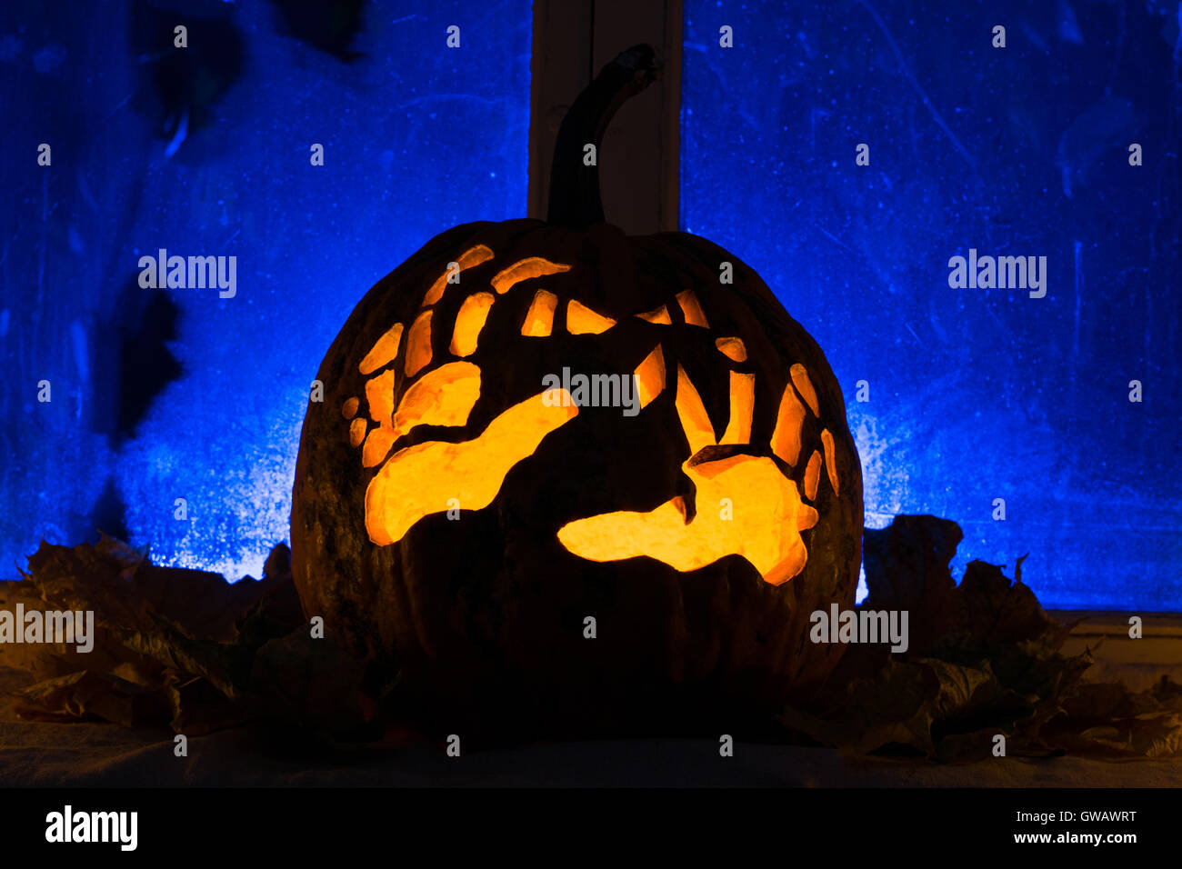 Foto für einen Urlaub, Halloween, Kürbis mit Händen gegen einen alten Fenster mit Herbstlaub Stockfoto