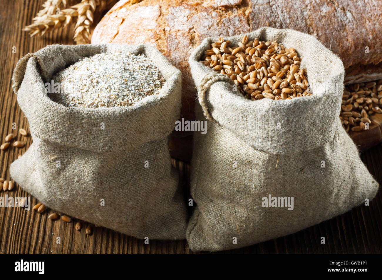 Weizen und Vollkornmehl in kleinen Beuteln auf Holztisch Stockfoto
