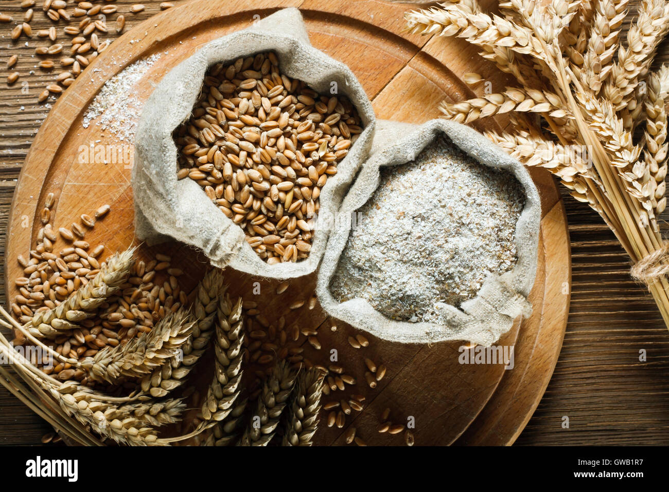 Weizen und Vollkornmehl in kleinen Beuteln auf Holztisch Stockfoto