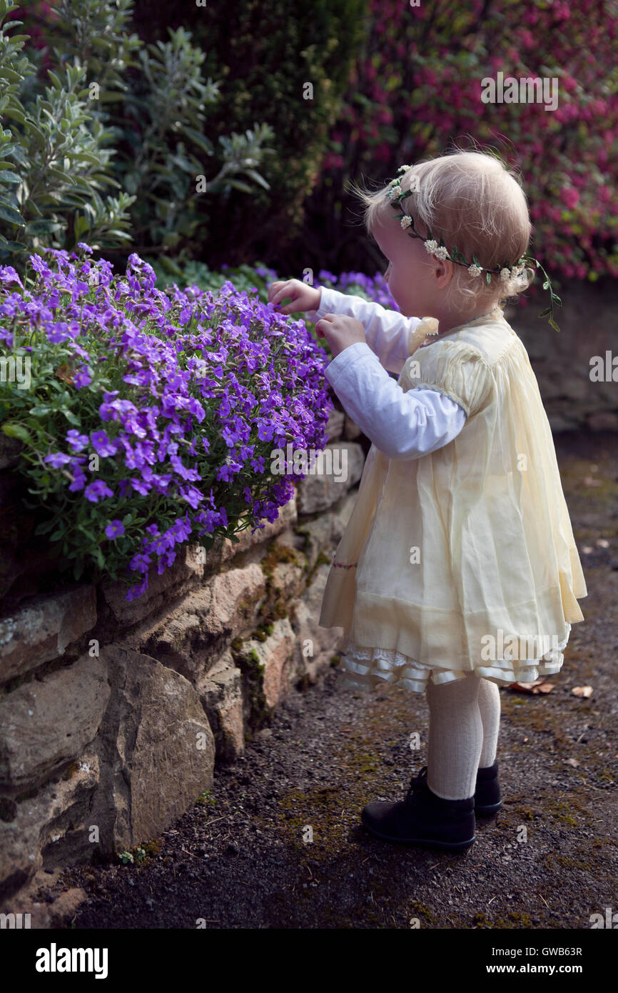 Kleinkind untersuchen lila Frühlingsblumen Stockfoto