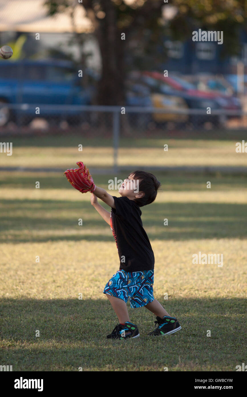 Ein kleiner Junge bereitet einen Fly Ball zu fangen, während des Trainings für Baseball in Cairns, Australien Stockfoto