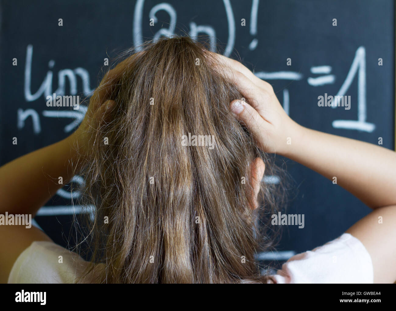 Schulmädchen denkt an die schwierige Aufgabe der Mathematik auf Tafel Stockfoto