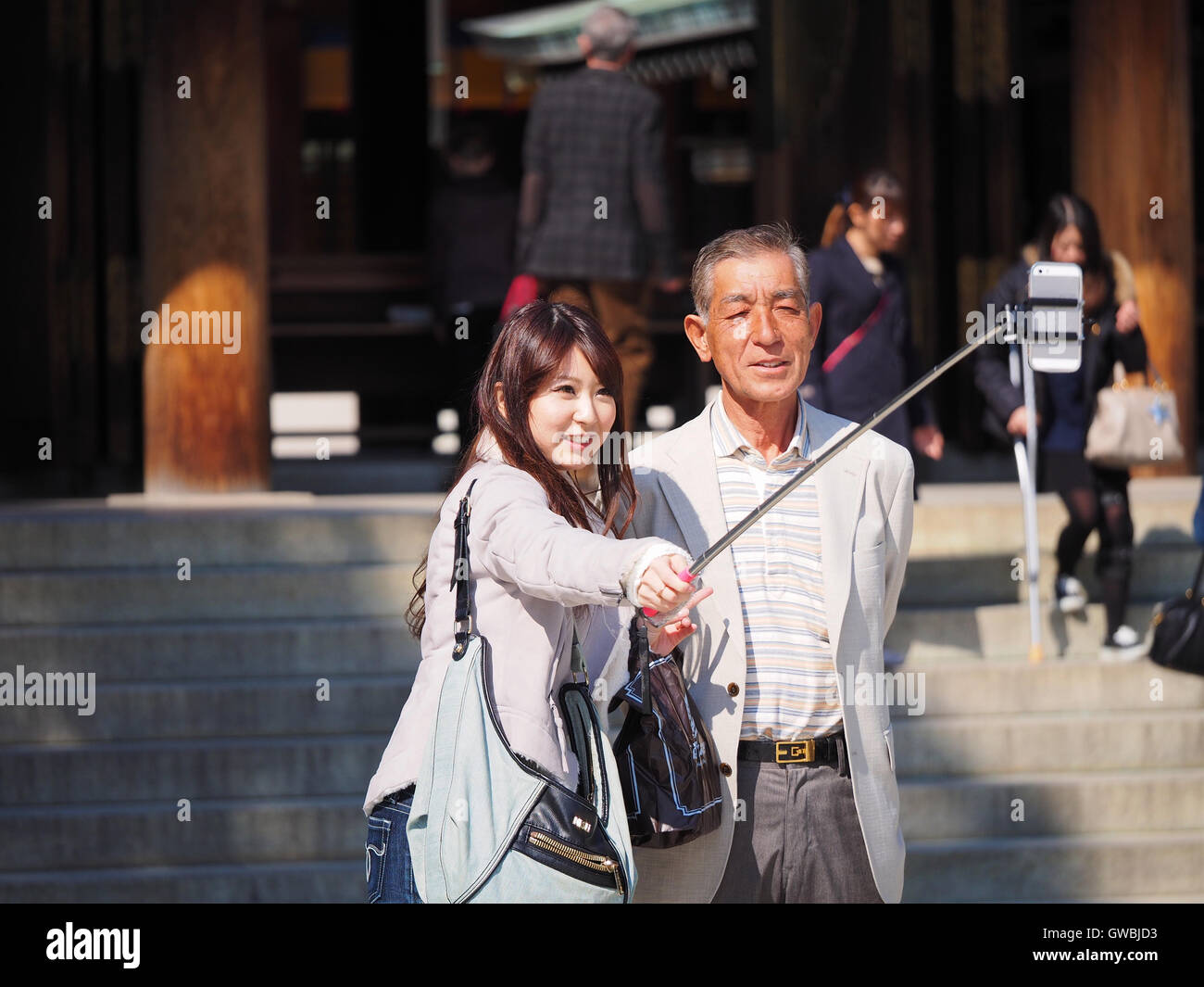 Eine junge Frau mit einem Mitte im Alter Mann unter einem Wefie mit einem Selfie-Stick am Meiji-Schrein, Tokyo, Japan Stockfoto