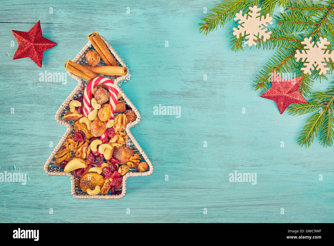Retro getönten Weihnachtsbaum geformte Behälter gefüllt mit Nüssen und getrockneten Früchten auf einem rustikalen Holztisch, Ansicht von oben mit Textfreiraum Stockfoto