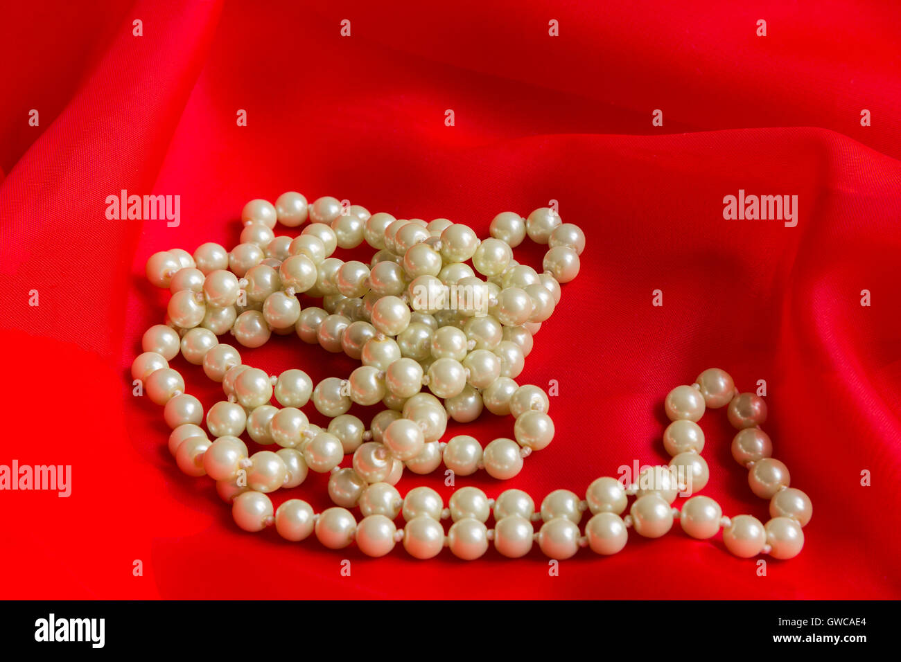 Perlenkette auf eine rote Seide Stockfoto