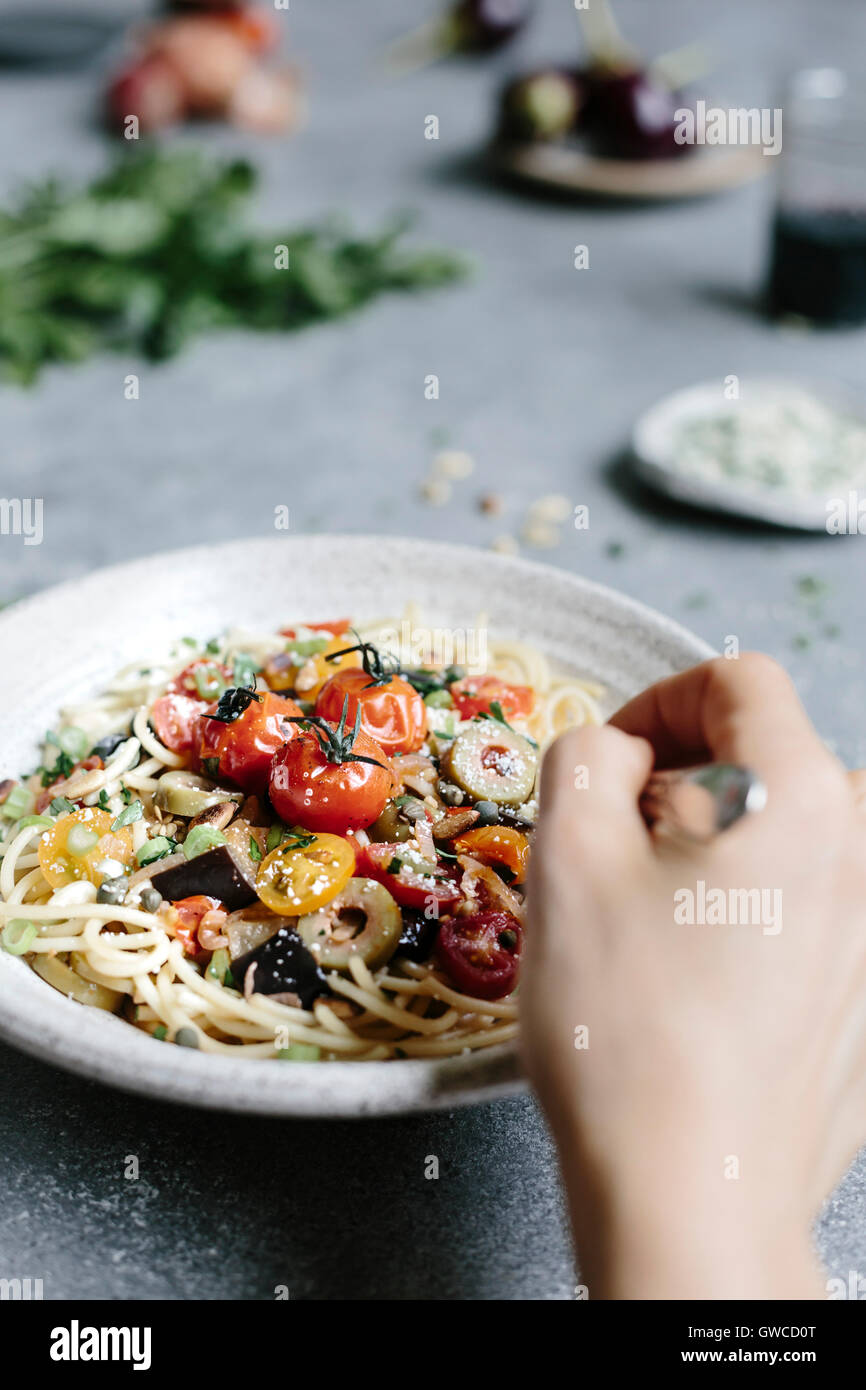 Eine Schüssel mit Nudeln Aubergine Pomodoro wird fotografiert, wie eine Frau es zu essen. Stockfoto