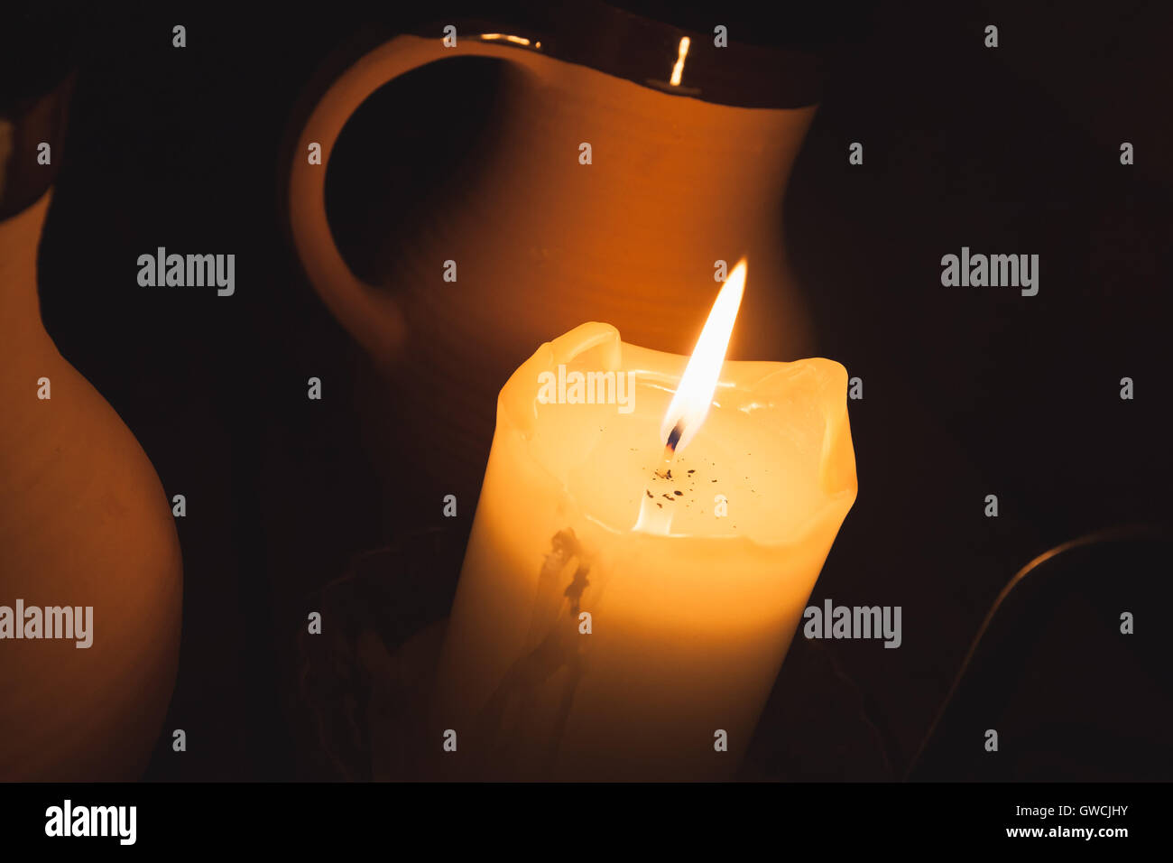 Brennende Kerze und Vintage Ton Becher Bier am Tisch im alten restaurant Stockfoto